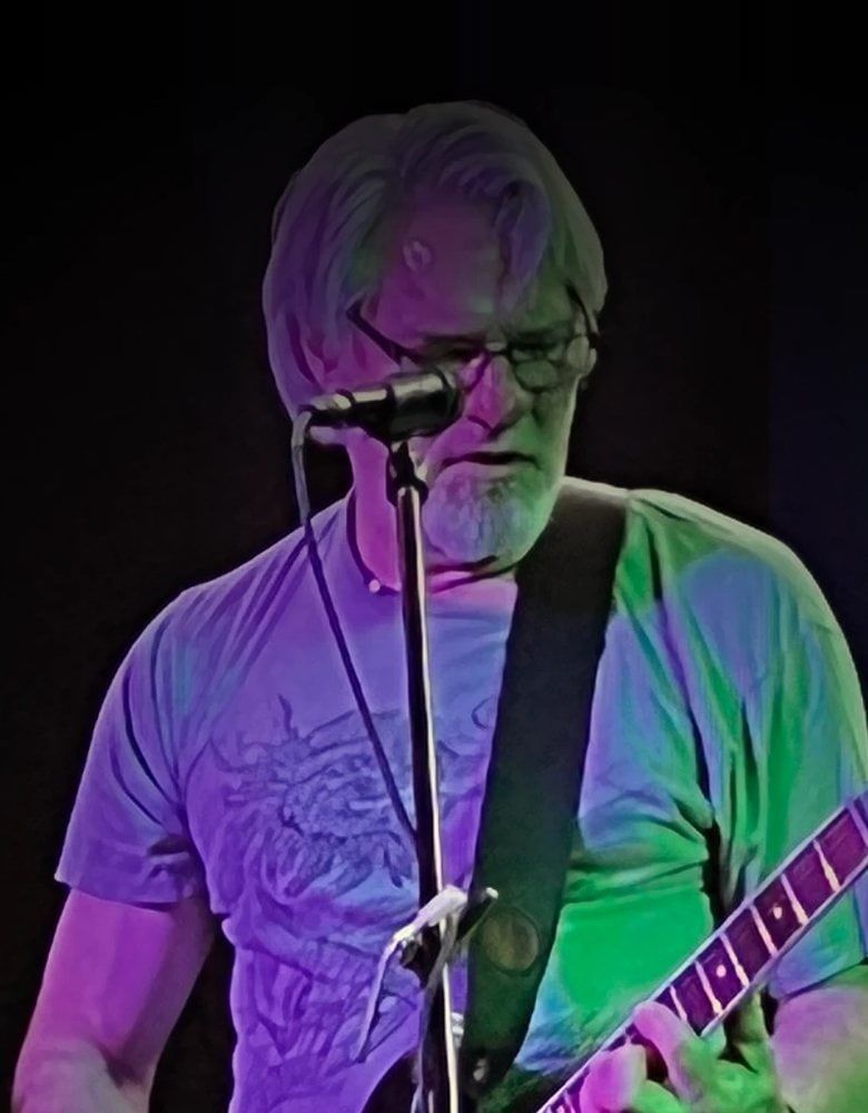 Portrait of Frank Oelschlager playing guitar at a microphone